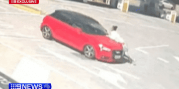 Автомобиль резко сворачивает с дороги, пытаясь избавиться от женщины, цепляющейся за капот.